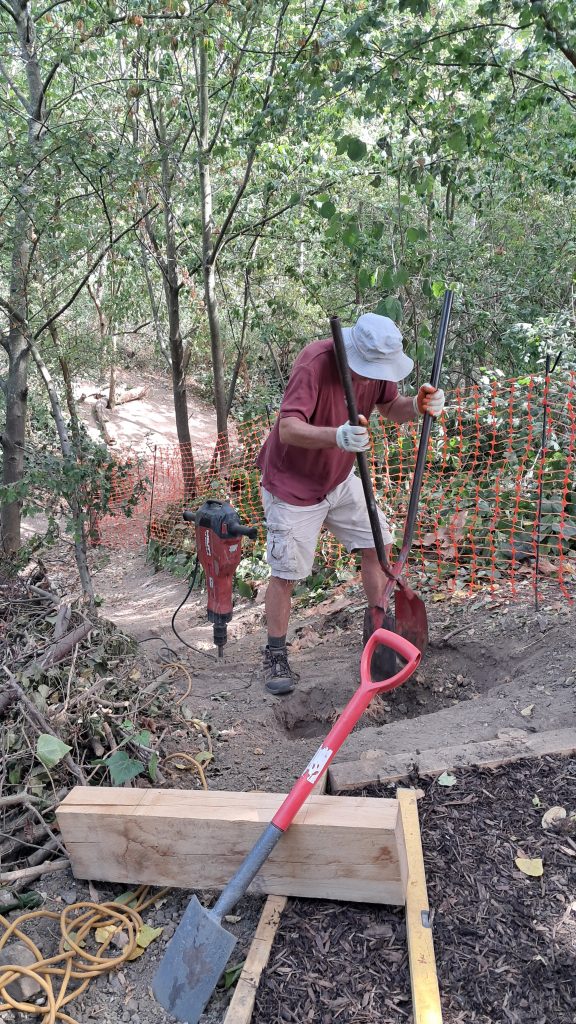 Volunteer and equipment digging out the ground to make depression to prepare for steps.